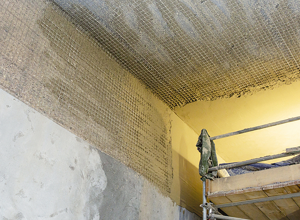 Großaufnahme des Maschengitters der Bewehrung aus Edelstahl an der Tunneldecke und am oberen Rand der Wand.