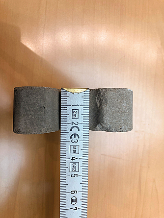 Asbest-Abstandshalter mit angelegtem Maßband zur Bestimmung der Dicke bzw. des Durchmessers.