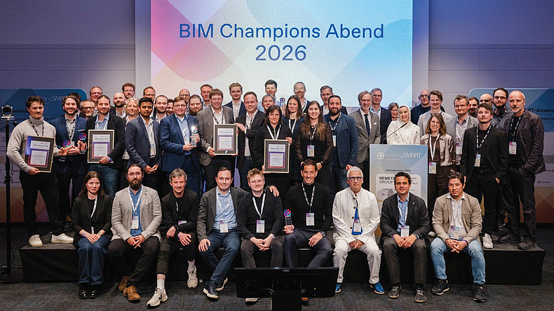 Gruppenfoto von rund 50 Personen auf einer Bühne vor einer Leinwand mit der Aufschrift „BIM Champions Abend 2026“; mehrere Personen halten gerahmte Auszeichnungen.