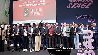 Gruppe von Menschen steht auf einer Bühne und hält Auszeichnungen; im Hintergrund eine Präsentationswand mit der Aufschrift „DIGITAL BAU“.