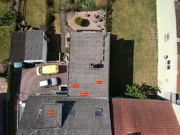 Hier vermisst die Drohne auf zwei benachbarten Dachflächen die Abstände von einer Abgasanlage zu den Fenstern beziehungsweise zur Gaube des Nachbargebäudes.