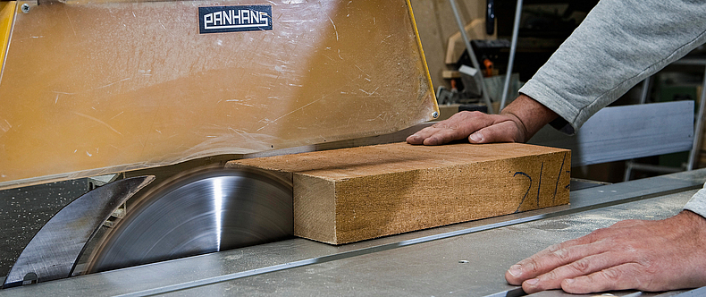 Baukreissäge beim Schnitt eines Holzstückes mit hochgeschobener Sicherheitshaube.