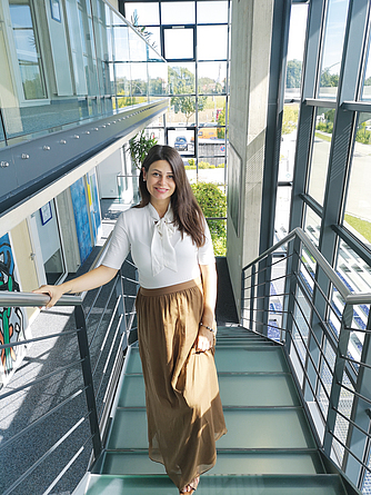 Frau steht auf Treppe und lächelt in die Kamera.
