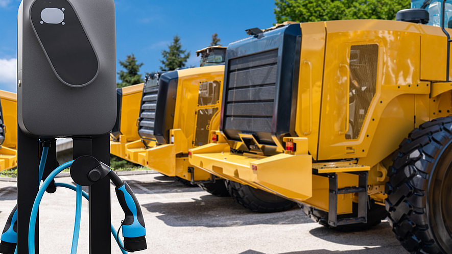 Mehrere Radlader stehen um eine Ladesäule herum.