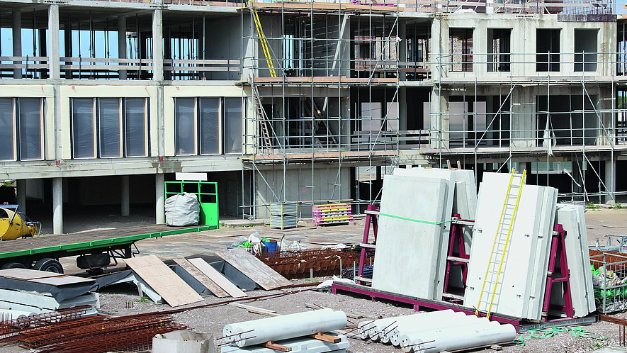 Baustelle eines Neubaus Auf einer Baustelle befinden sich Baumaterialien vor einem Neubau.