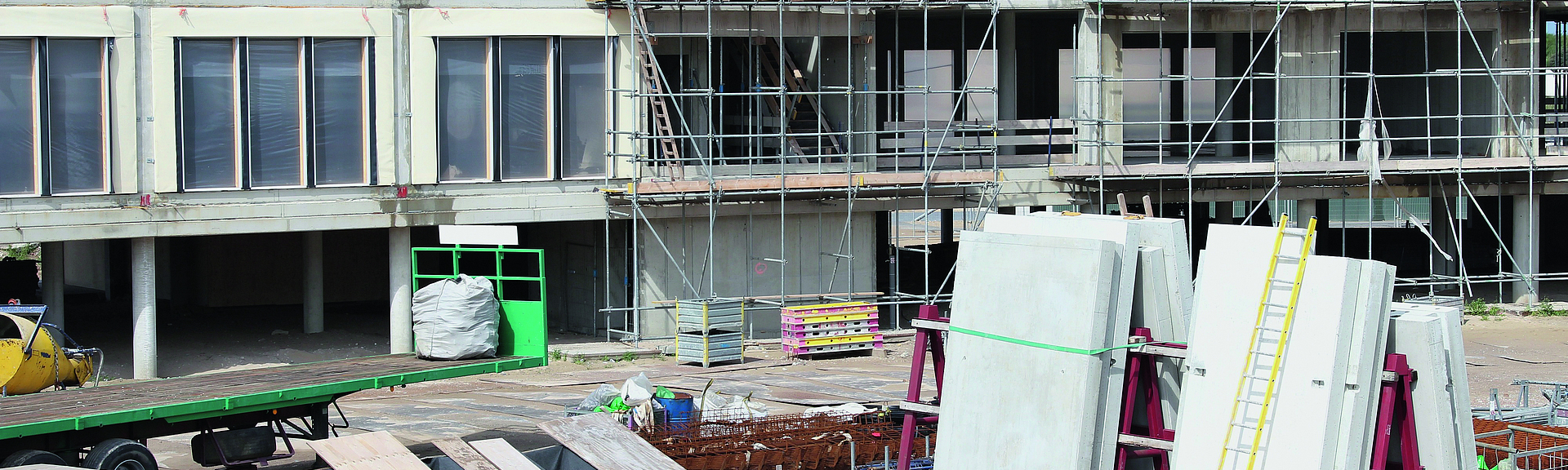 Baustelle eines Neubaus Auf einer Baustelle befinden sich Baumaterialien vor einem Neubau.