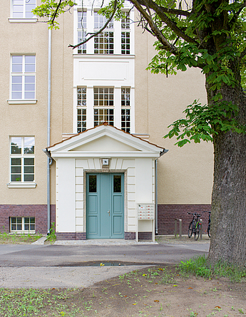 Alte Kämpfer an den Haustüren wurden ebenfalls erhalten. Bossierungen (überstehende, herausstehende Elemente) sind mit Glattputz nachgestellt. Detailaufnahme eines vorgesetzten Haustürbereichs mit eigenem Dach.