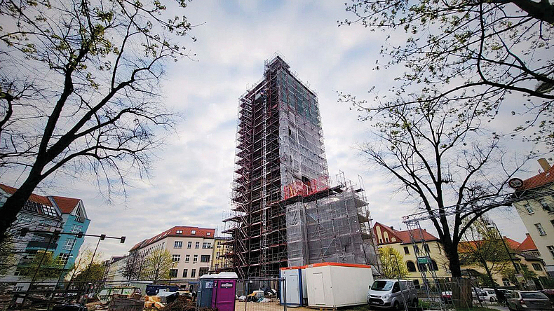 Hohes Gebäude im Bau, vollständig von Gerüst umgeben, in einer städtischen Umgebung.