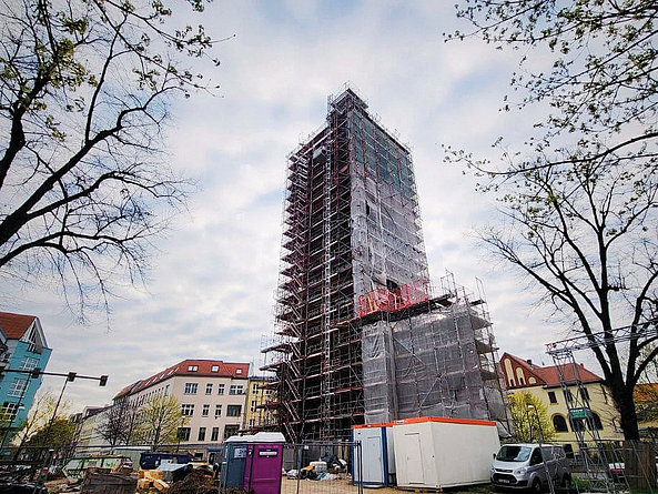 Hohes Gebäude im Bau, vollständig von Gerüst umgeben, in einer städtischen Umgebung.