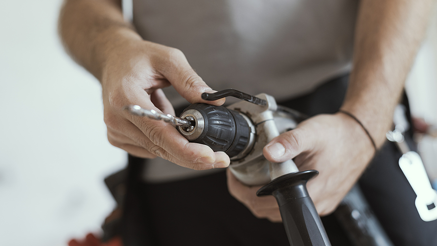Handwerker wechselt Bohrer Ein Handwerker wechselt einen Bohrer.