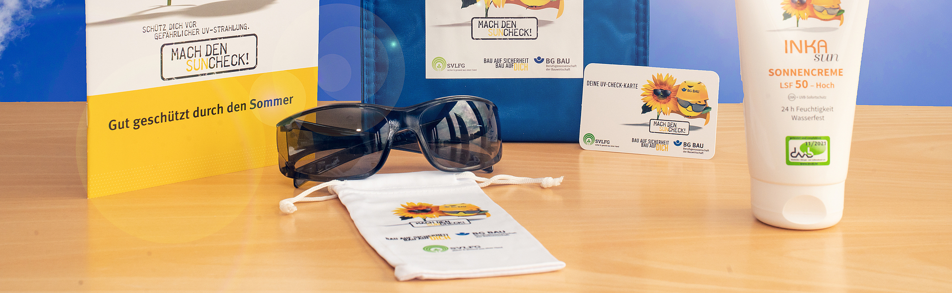 Zusammenstellung des UV-Schutz-Pakets: Sonnencreme, Sonnenbrille mit Beutel, UV-Check-Karte und Informationsmaterial zum UV-Schutz