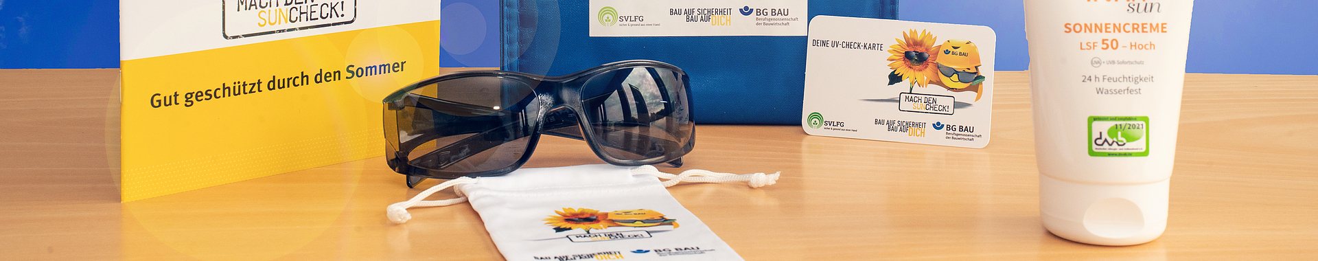 Zusammenstellung des UV-Schutz-Pakets: Sonnencreme, Sonnenbrille mit Beutel, UV-Check-Karte und Informationsmaterial zum UV-Schutz