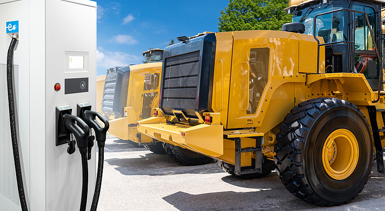 Ein Radlader steht vor E-Ladestation.