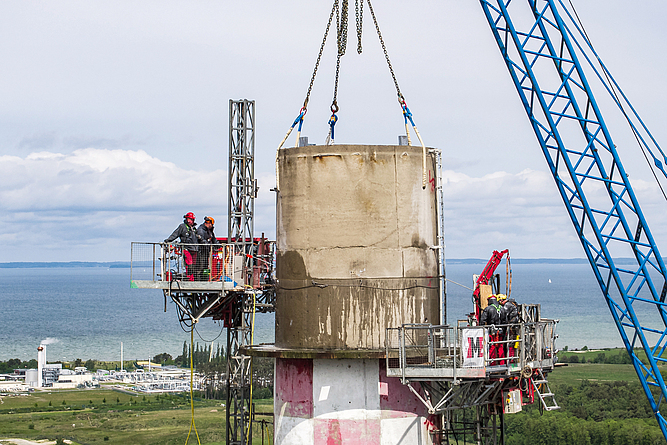 Abb. 2: Im Schutze von mastgeführten Kletterbühnen wird der Schornstein horizontal in Kreis-Segmente zersägt und abgebrochen.