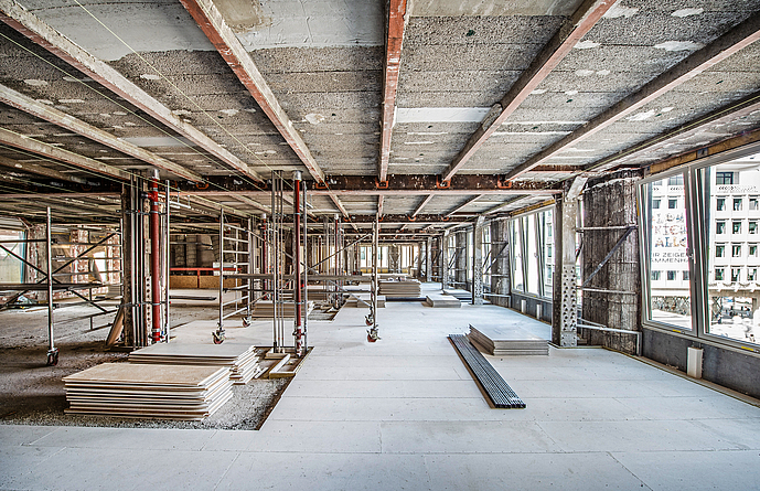 Baustelle in einem Gebäude, in dem Decken- und Fußbodenarbeiten durchgeführt werden. Fast der gesamte Fußboden wurden schon mit Platten ausgelegt.