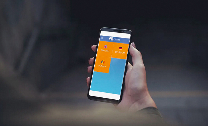 Hand hält ein Mobiltelefon mit der "Epoxy Europe Safety Training"-App.