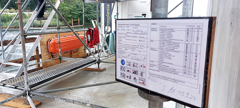 Sicherheitseinrichtungen an einem Pfeiler-Fundament im Borgstedter See: Schleifkorbtrage, davor Rettungswesten (li.) und Erste-Hilfe-Station (Hintergrund) Sicherheitseinrichtungen an einem Pfeiler-Fundament im Borgstedter See: Schleifkorbtrage, davor Rettungswesten und Erste-Hilfe-Station.