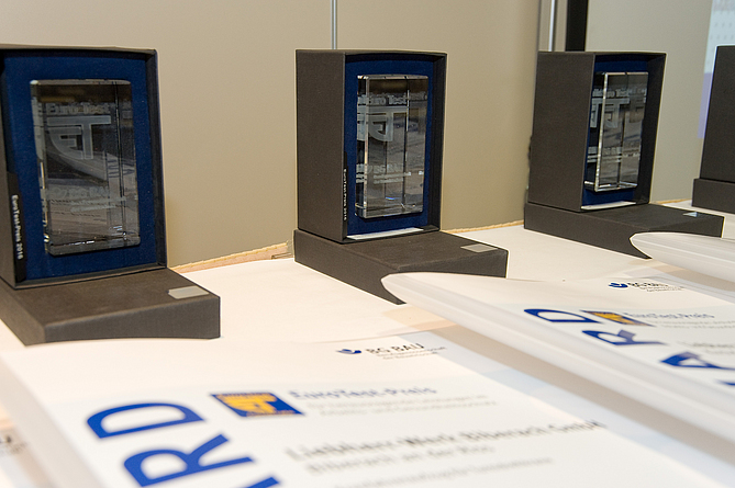 Auf einem Tisch stehen die EuroTest-Preise mit den Auszeichnungen.