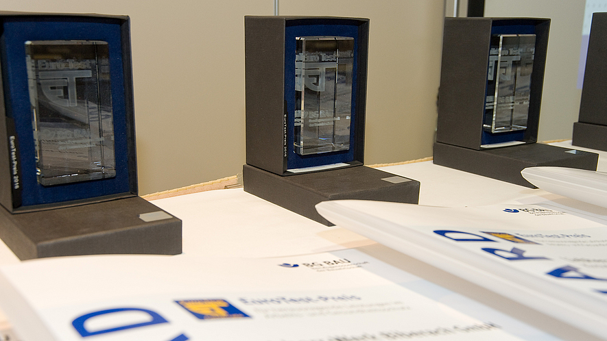 Auf einem Tisch stehen die EuroTest-Preise mit den Auszeichnungen.