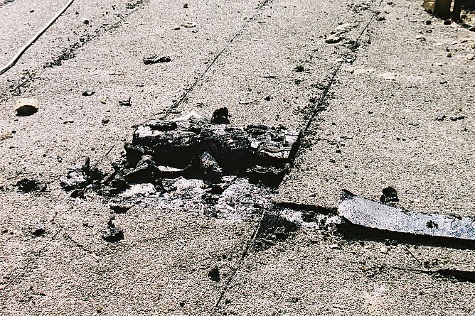 Beschädigte Asphaltoberfläche mit Ausbruchstelle und Rissen.