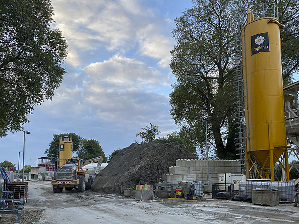 Baustelle mit einem großen Haufen Abraummaterial, das von einem Radlader aufgenommen wird.
