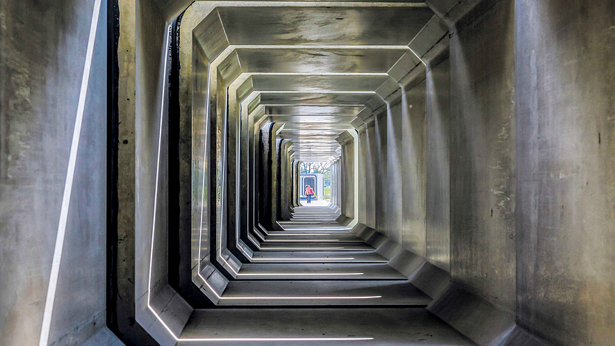 Betonkanal Ein Blick in das Innere eines Betonkanals. Am anderen Ende steht eine Person.