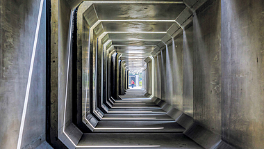 Betonkanal Ein Blick in das Innere eines Betonkanals. Am anderen Ende steht eine Person.