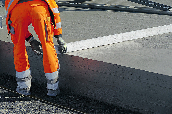 Ein Beschäftigter zieht einen Längsglätter über eine frisch eingebaute Betonbahn des Flugfelds.
