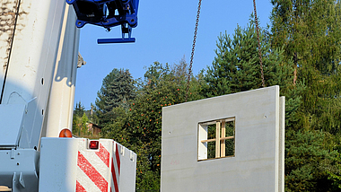 Beton-Fertigteile werden mit einem Kran zu einem Fertigteilhaus zusammengesetzt.