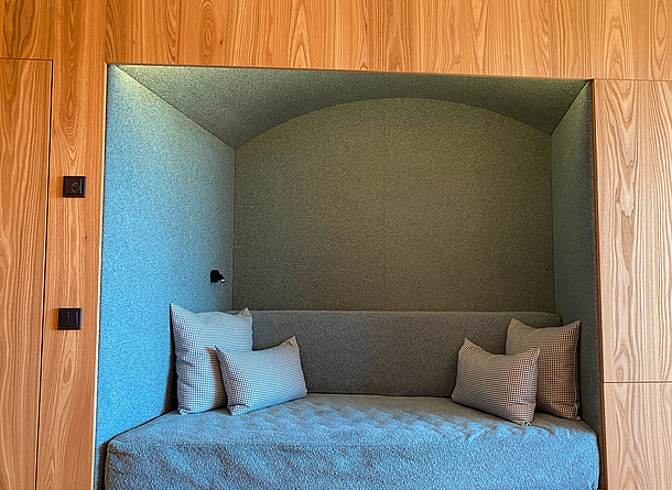 Verwendung von Ulmenholz bei den eingelassenen Nischen im Zimmer In einer Nische mit Holzrahmen steht ein Bett.