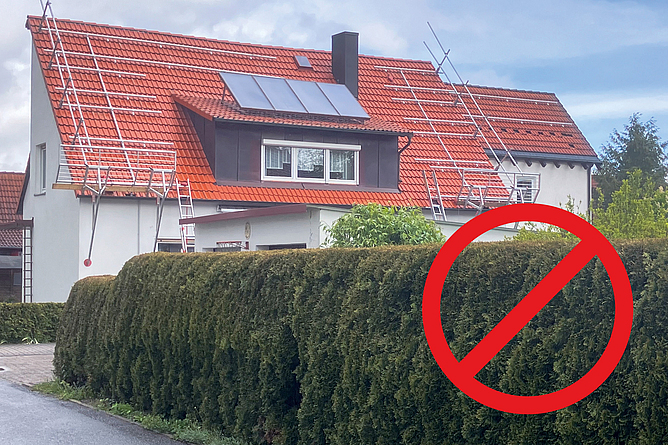 Einfamilienhaus, auf dessen Dach Seitenschutzsysteme angebracht sind. Das Dach ist über Leitern erreichbar und die Systemteile sind nur an den jeweiligen Außenbereichen des Hauses angebracht und fehlen an anderen Stellen.