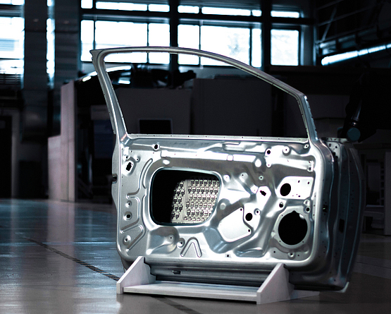 Ausgebaute, glänzende Fahrzeugtür in einer Halle.