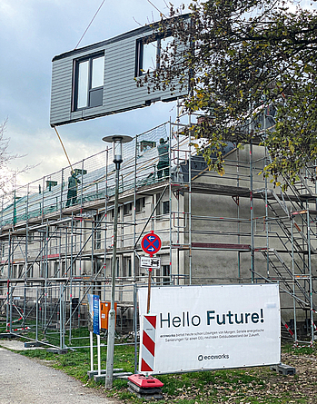 Das LEG-Zukunftshaus während der energetischen Sanierung. Ein vorgefertigtes Fassadenelement inklusive Fenster und Dämmung wird per Kran aufgesetzt.