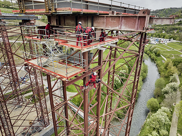 Training Höhenrettung auf Stahl-Hilfskonstruktion auf Porr-Baustelle Hochbrücke Horb Personen mit Helm, Schutzkleidung und persönlicher Schutzausrüstung gegen Absturz auf einer Stahlkonstruktion, einer seilt sich ab.