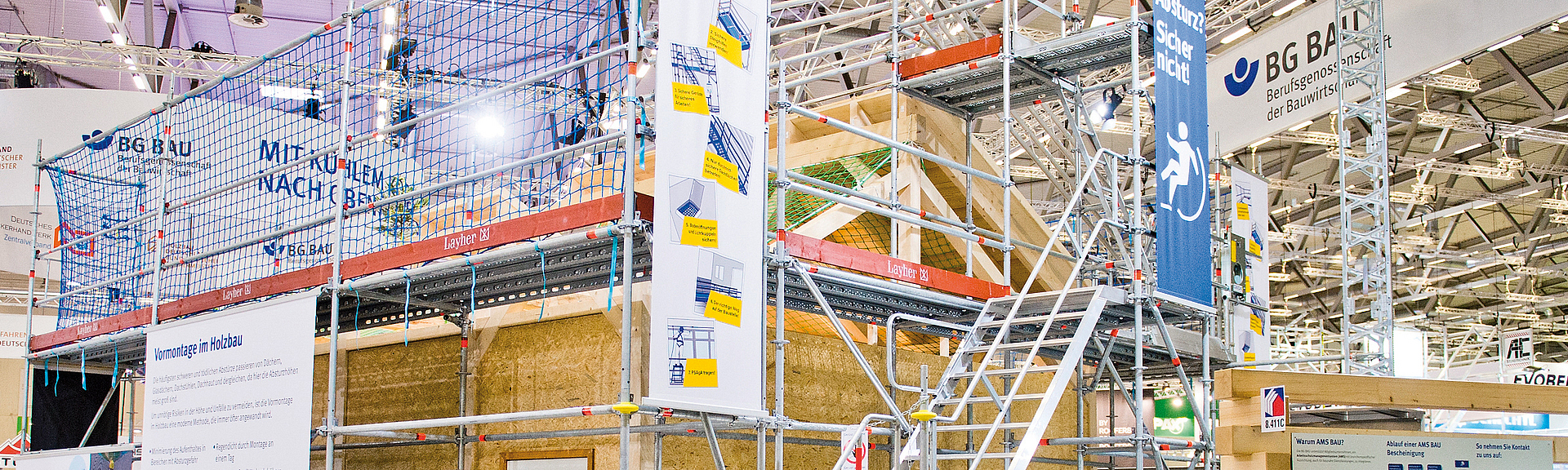 Messestand mit offenem Holzhaus, an dem draußen Gerüste und Treppen angebracht sind.