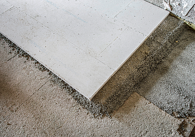 Platte, die auf einen graubraunen Untergrund gelegt wird.