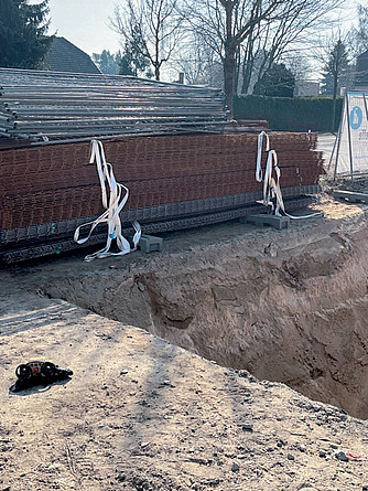 Lagerung von Bewehrungsmatten an einer unzureichend geböschten Baugrube (>45 Grad) Aufgeschichtete Bewehrungsmatten an einer steilen Baugrube.