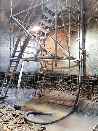 Unterer Teil eines aufgehängten Treppenturms, der auf dem Boden einer Baugrube ankommt.