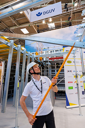 Vorführung eines modularen Trägersystems für Deckenschalung, das vom Boden aus montiert wird, am bauma-Messestand der BG BAU. Mit einer Montagegabel wird ein Querträger in einen Hauptträger eingehängt.