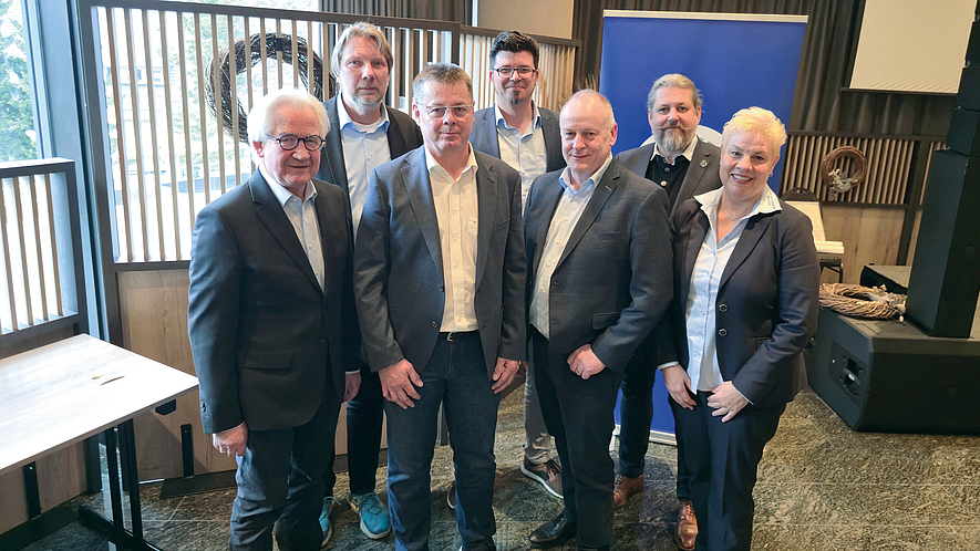 Gruppenbild mit sieben Personen in einem Innenraum.
