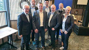Gruppenbild mit sieben Personen in einem Innenraum.