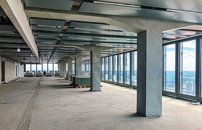 Reduzierung auf das Wesentliche: Sichtbeton als gestalterisches Element in allen Etagen Fertiggestellter Rohbau einer Etage mit Betonpfeilern und Glasfront.