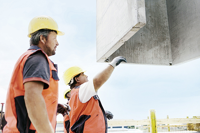 Zwei Arbeiter stehen an einer Baggerschaufel.