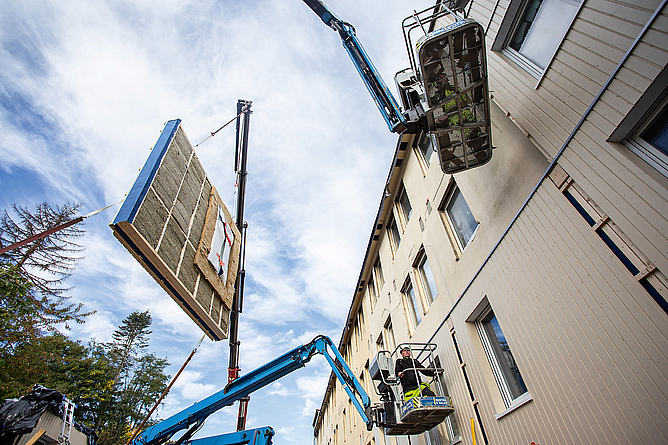 Das LEG-Zukunftshaus während der energetischen Sanierung. Ein vorgefertigtes Fassadenelement inklusive Fenster wird per Kran aufgesetzt.