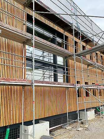 Gerüst vor dem Gebäude mit Holzfassade