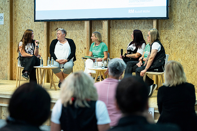 Blick aus den Zuschauerreihen auf das Podium, wo gerade fünf Frauen diskutieren.