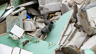 Bauabfälle aus unterschiedlichen Materialien in unsortierter Anhäufung: Mauersteine, Rigips-Platten, PVC-Rohrstücke, Aluminiumbleche.