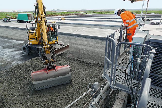 Der Beton wurde mit einem Bagger vor dem Gleitschalungsfertiger abgelegt und anschließend mit dem Verteilerschwert der Maschine gleichmäßig verteilt. 