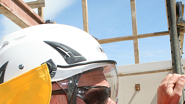 Person in UV-Schutzkleidung Eine Person mit UV-Schutzkleidung steht auf einer Baustelle.