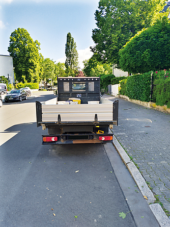 Ansicht eines LKW von hinten: Auf der Ladefläche wird Abfall transportiert. Allgemeine Vorschriften wie die zur Ladungssicherung werden eingehalten.